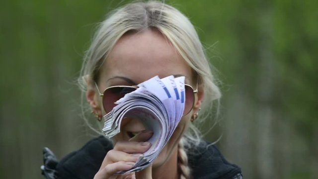 Girl with a pack of 500 Euro bills, showing off and smiling.