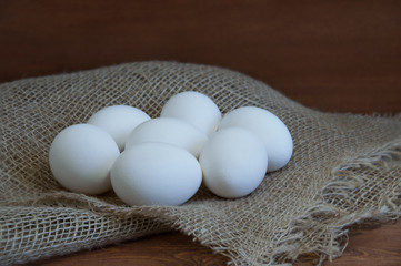 White chicken eggs on a non-woven fabric on a wooden brown background.Cose-up.