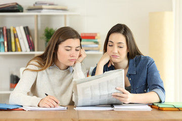 Two bored students reading a newspaper