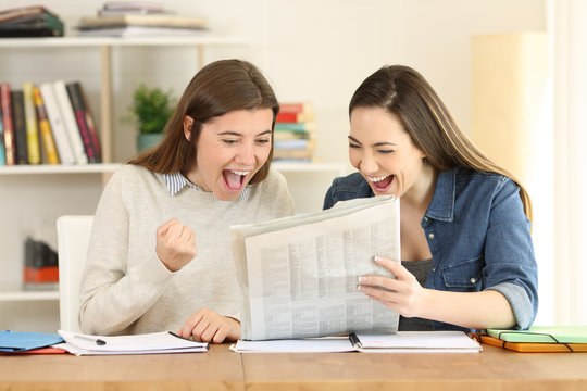 Two excited students reading a newspaper