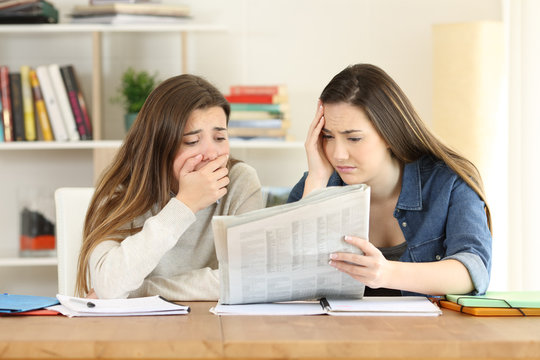Two worried students reading a newspaper
