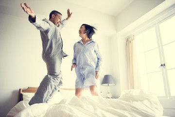 A couple jumping on the bed