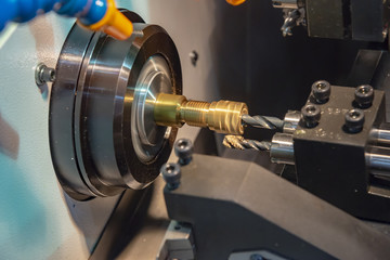 The CNC lathe machine cutting the brass shaft with the drill tool.The high technology manufacturing concept.