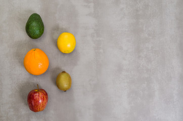 Great concept of healthy eating, various fruits on gray background, polished concrete. Orange, apple, kiwi, lemon.