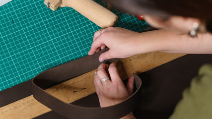 Tanner measures leather billet. Working process in workshop