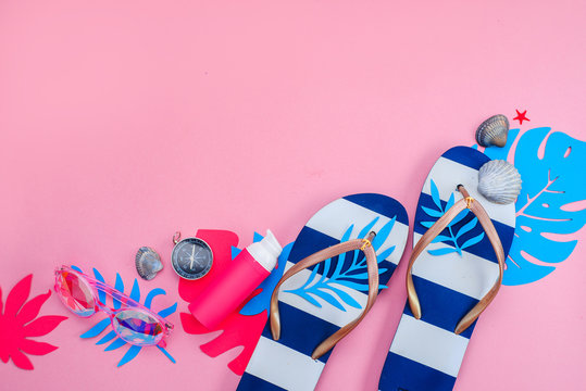 Beach accessories, flip flops, tropical leaves, seashells flat lay. Colorful travel and vacation concept on a bright pink background with copy space.