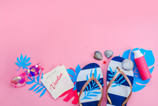 Feminine summer vacation essentials concept. Flip flops, sunglasses and sunscreen on a vibrant pink background with copy space. Colorful travel flat lay with tropical leaves.