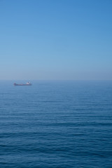 Cloudy horizon and Fog over the sea waves, natural background, red cargo ship on the horizon