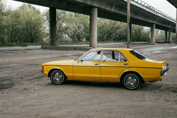 yellow vintage classic car under bridge