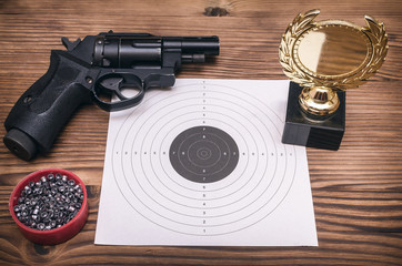 Obraz premium Best shooter award background with copy space. Winner in shooting. Gun, paper target and gold medal. Shooting range.
