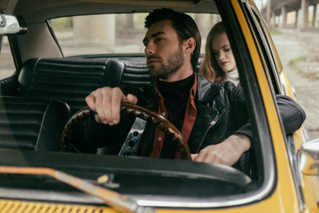 Fototapeta na wymiar handsome young man driving retro car and girlfriend sitting behind