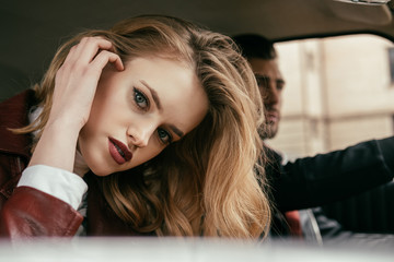 Fototapeta premium beautiful stylish young woman looking at camera while boyfriend driving car