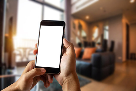 A man hand holding smart phone device in the bright office room interior.
