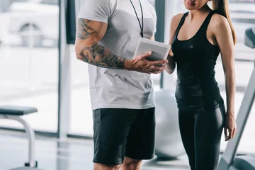 Rollo cropped image of male personal trainer showing schedule on digital tablet to sportswoman at gym © LIGHTFIELD STUDIOS