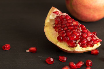 Pomegranate fruit slice and seeds still life on rustic black background
