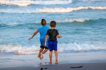 Two Children playing on sandy beach near sea
