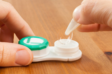 hands taking out the contact lens from the container