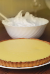 Preparing Lemon Pie. Lemon Pie and Bowl with Meringue Cream Ready to be Decorated on Wooden table, closeup.