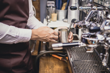 Male barista using machine for make coffee at cafe. Vintage tone.