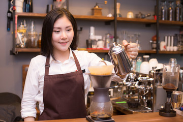 Asian women Barista smiling and looking to camera in coffee shop counter.  Barista female working at cafe. Working woman small business owner or sme concept.
