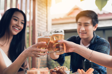 Close up of beer glass with asian people drinking beer in restaurant.