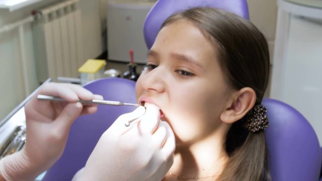 Closeup 4k footage of dentist in latex gloves inspecting girl's mouth