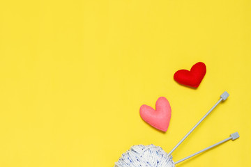 Top view of yarn and red felt heart on yellow background, love to knit image concept
