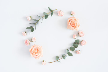 Flowers composition. Wreath made of rose flowers, eucalyptus branches on pastel gray background....