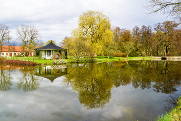 Fototapeta premium Vittskovle, Sweden. White and black gazebo with reflections in motionless water on a cloudy spring day.