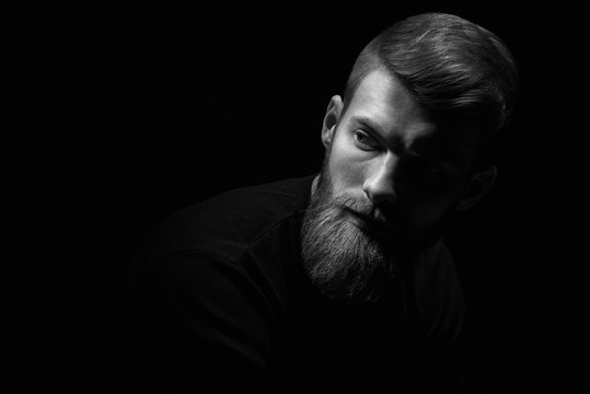 Close up image of serious brutal bearded man on dark background Confident and dramatic concept