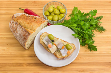 Open sandwich with pickled herring fillet and some ingredients beside