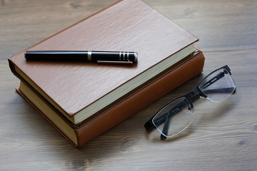 Book, notebook, pen and glasses on the desk. Business, science and education. Working background.