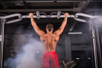 Handsome Muscular Man With Perfect Body Doing Pull Ups in gym