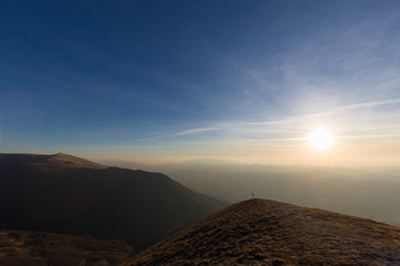 Cross on top of Mt. Serrasanta (Umbria, Italy), with warm golden hour colors and sun low on the horizon