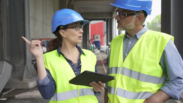 Recycling industry workers using tablet outside factory