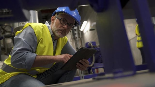 Industrial technician connected with tablet in recyling plant