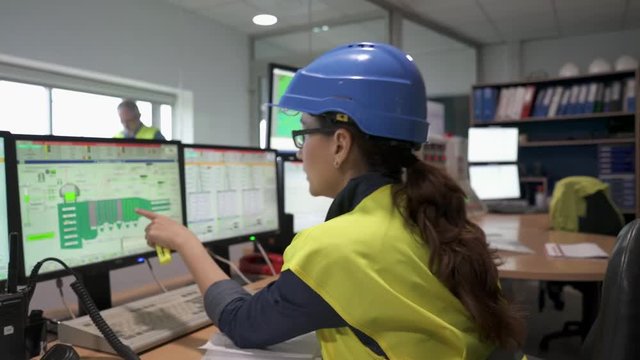 Woman in industrial control room using radio to give instructions