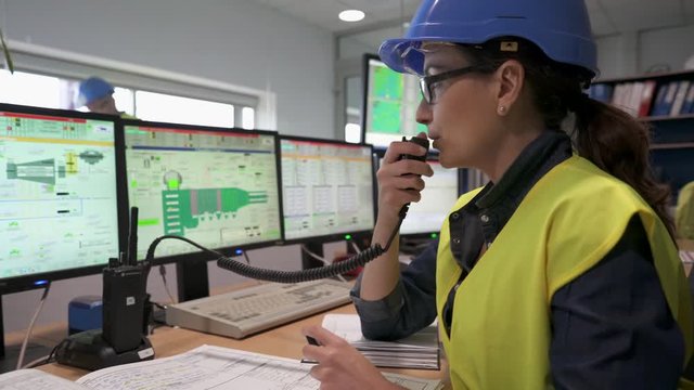 Woman in industrial control room using radio to give instructions