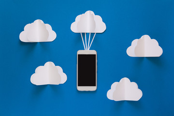 Network connection and cloud storage technology concept. Data communications and cloud computing network concept. Smart phone flying on paper cloud. Origami. Paper cut. Top view