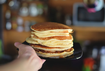 Plate with fluffy tasty pancakes in the hand