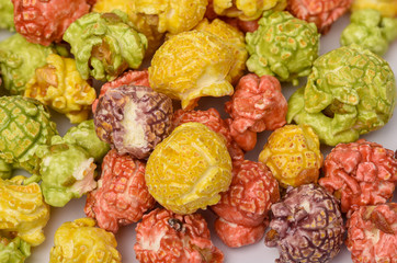 A pile of colorful caramel popcorn, still life for a holiday with colorful popcorn on white wooden table.