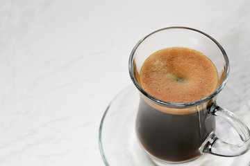 Espresso. Glass espresso cup with coffee beans on a light backgr