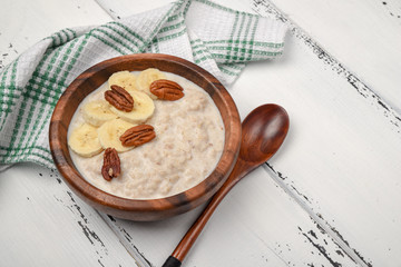 Oatmeal porridge with banana and pecan nuts for breakfast