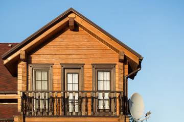 Part of modern wooden country house with blue sky on background. Roof of eco residential building near forest. Building and architecture of rustic chalet