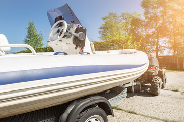 Transportation of inflatable boat on trailer. ATV quadbike moves ship to lake or river shore for launching. Beginnig of water navigation and fishing season © Kyryl Gorlov
