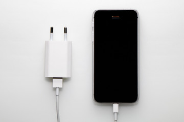 Black smartphone, adapter and cable on a white background