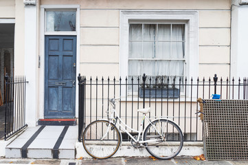 Fototapeta na wymiar Facade of a traditional town house and a bicycle on the fence in London, England, UK