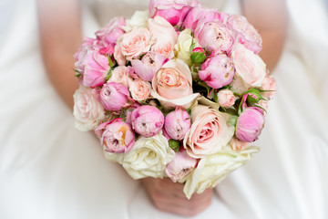 a wedding bouquet of roses and peonies in the hands of the bride. close-up. On a blurred background