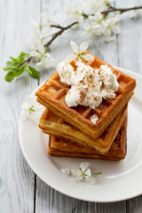 delicious Viennese waffles with ice creamon saucer in spring composition on wooden background