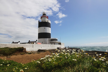 Fototapeta na wymiar Black and white lighthouse and surrounding landscape at Ireland coastline